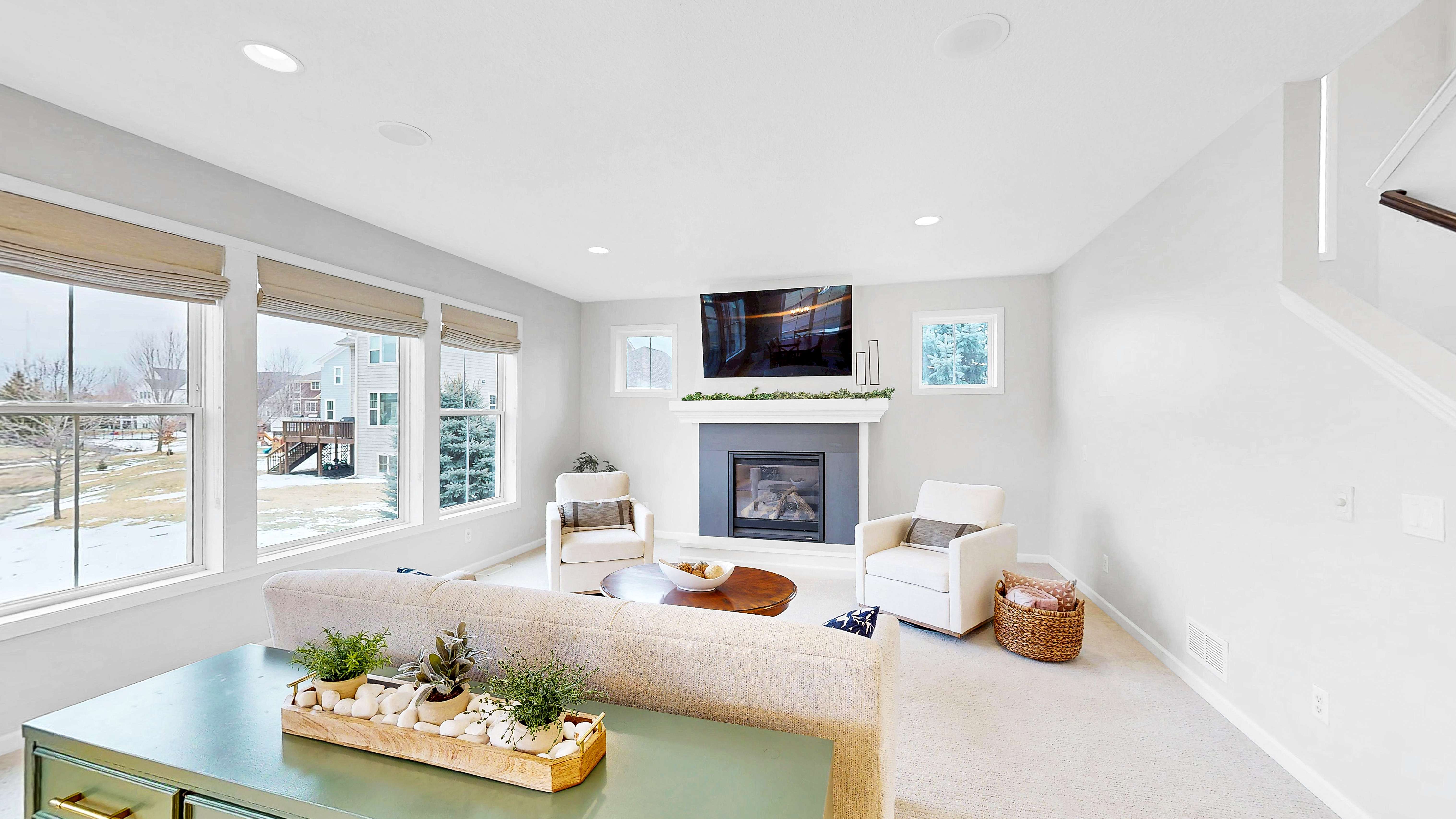 Living room with gas fireplace and large windows overlooking the green space